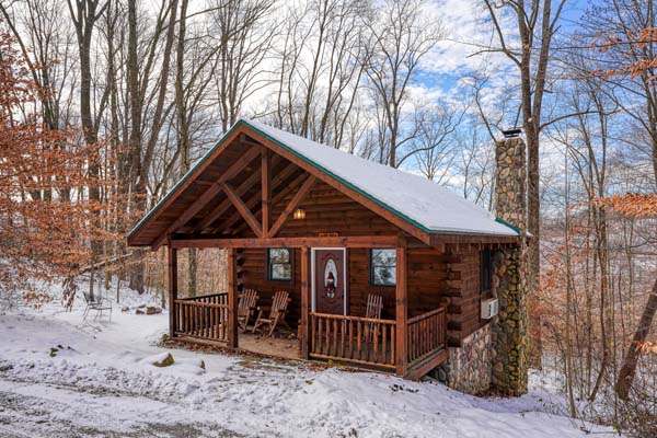 Bear Hugs log cabin with stone chimney in a snowy clearing