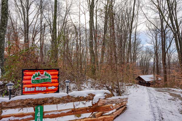 Snow covered driveway with the red cabin sign
