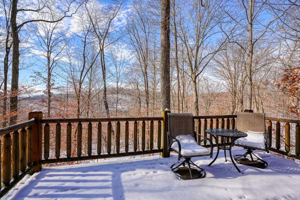 Snow covered deck with table and chairs looking into the woods