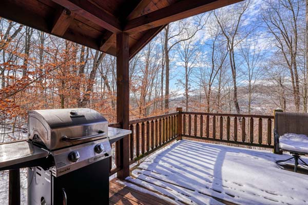 Snow covered deck with gas grill