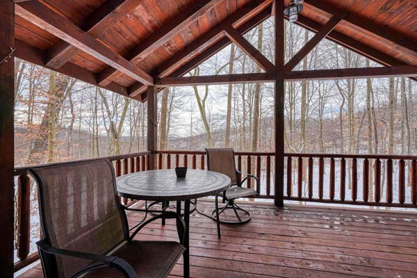 Covered deck with table and chairs facing the woods